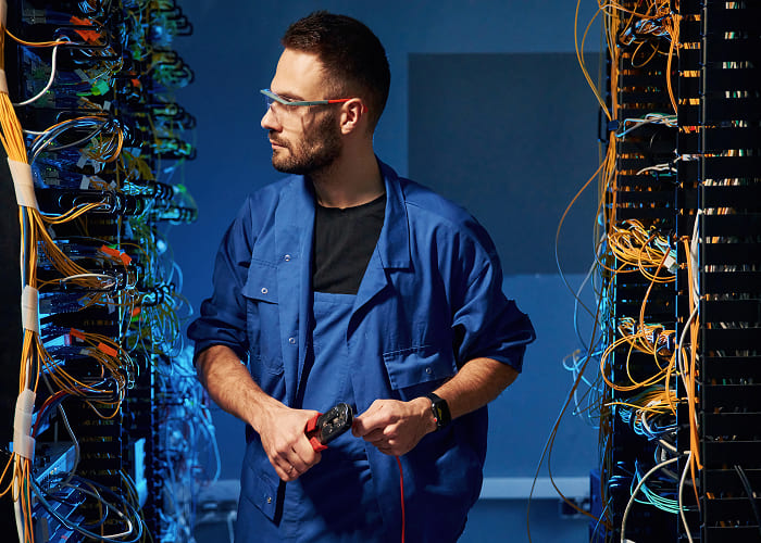Técnico inspecionando conexões e cabeamento em ambiente de telecomunicações